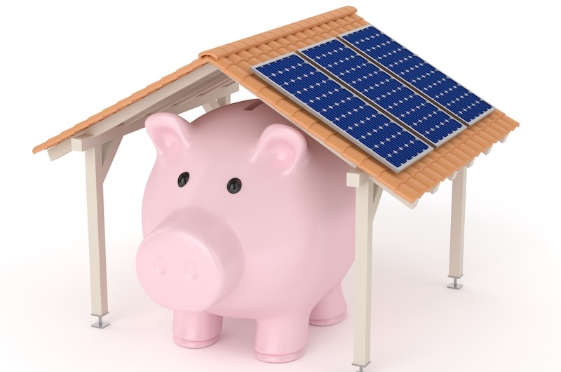 Sparschwein unter einem Dach mit Photovoltaik-Modulen