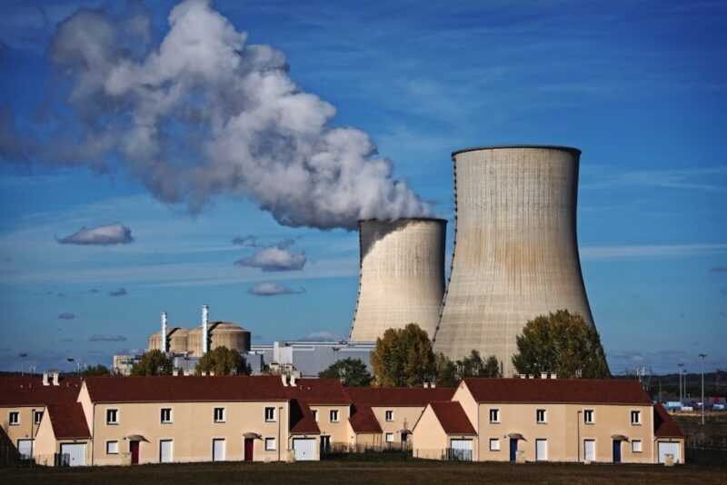 Ein Atomkraftwerk und dessen Kühltürme hinter eine Wohnsiedlung.