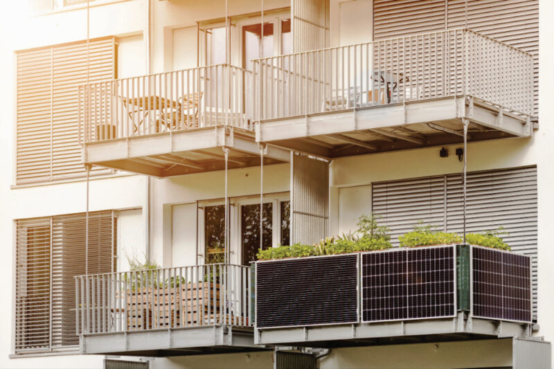 Vier Balkone an einem Haus, davon ist einer mit einer Steckersolaranlage ausgestattet.