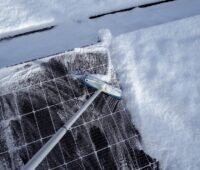 Ein Schrubber befreit Photovoltaik-Module im Winter von Schnee, Zendure empfiehlt das Balkonkraftwerk steil auszurichten, damit Schnee gar nicht erst anhaftet.