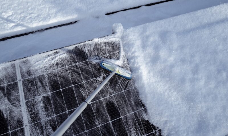 Ein Schrubber befreit Photovoltaik-Module im Winter von Schnee, Zendure empfiehlt das Balkonkraftwerk steil auszurichten, damit Schnee gar nicht erst anhaftet.