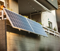 Ein kleines PV-Kraftwerk mit zwei Solarmodulen, die an einem Balkon befestigt sind.