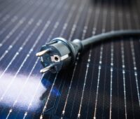 Als Untergrund ein Photovoltaik-Modul. Drauf liegt ein Schuko-Stecker