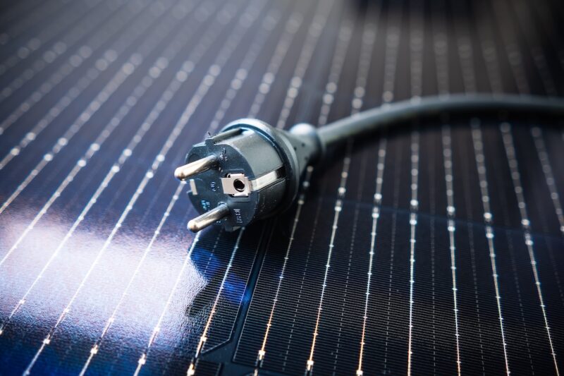 Als Untergrund ein Photovoltaik-Modul. Drauf liegt ein Schuko-Stecker