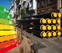 Eine Straße, dort rechts im Bild Rohre für die Fernwärme, die noch nicht in der aufgerissenen Straße verlegt wurden. Links die farbige Darstellung der Effizienzstufen. Beides als Symbol für die kommunale Wärmeplanung.