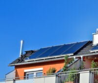 Auf dem Dach eines Hauses ist eine Solarthermie-Anlage installiert. Die Schornsteine deuten auf eine Gasheizung hin. Für solche Anlagen gibt es voraussichtlich bis Ende 2022 noch eine steuerliche Förderung.