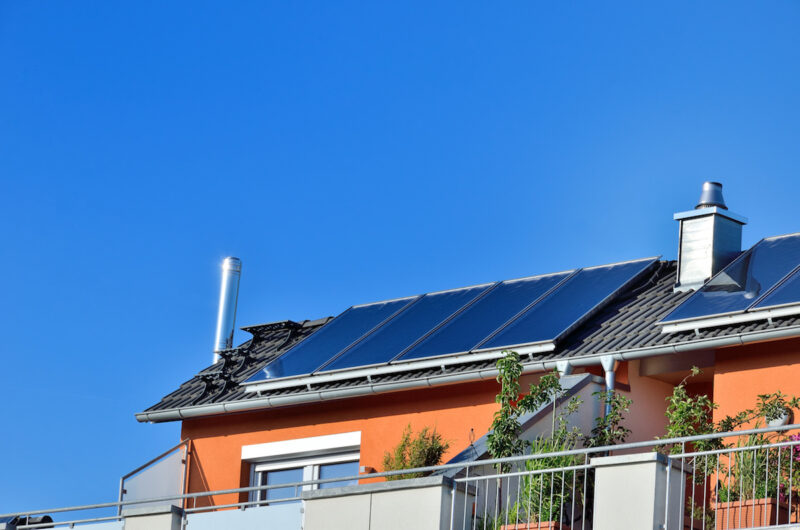 Auf dem Dach eines Hauses ist eine Solarthermie-Anlage installiert. Die Schornsteine deuten auf eine Gasheizung hin. Für solche Anlagen gibt es voraussichtlich bis Ende 2022 noch eine steuerliche Förderung.