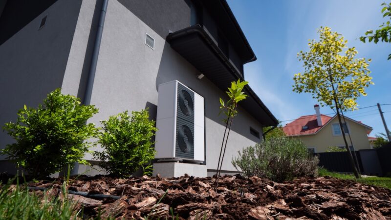Vor einem Gebäude steht eine Wärmepumpe.