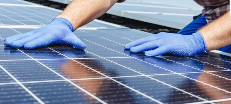 Zwei Hande mit Schutzhandschuhen bei der Handhabung von Solarmodulen.