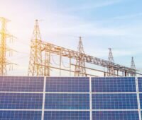 PV-Module vor Strommasten und blauem Himmel.