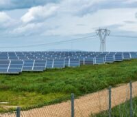 Freiflächen-Solarpark vor Stromleitung.