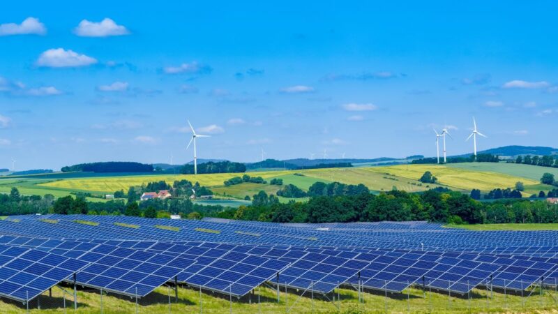 Malerische Landschaft mit Wiesen, Äckern, PV und Windenergie.
