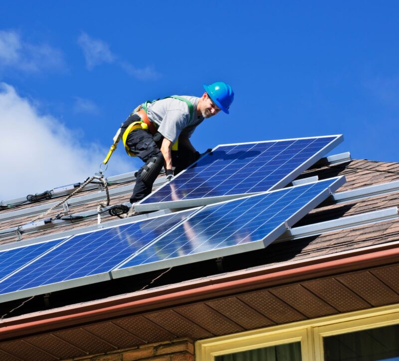 Ein Installateur verlegt Solarmodule auf dem Dach.
