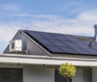 Hausdach mit PV-Anlage und am Giebel montierter Wärmepumpe.