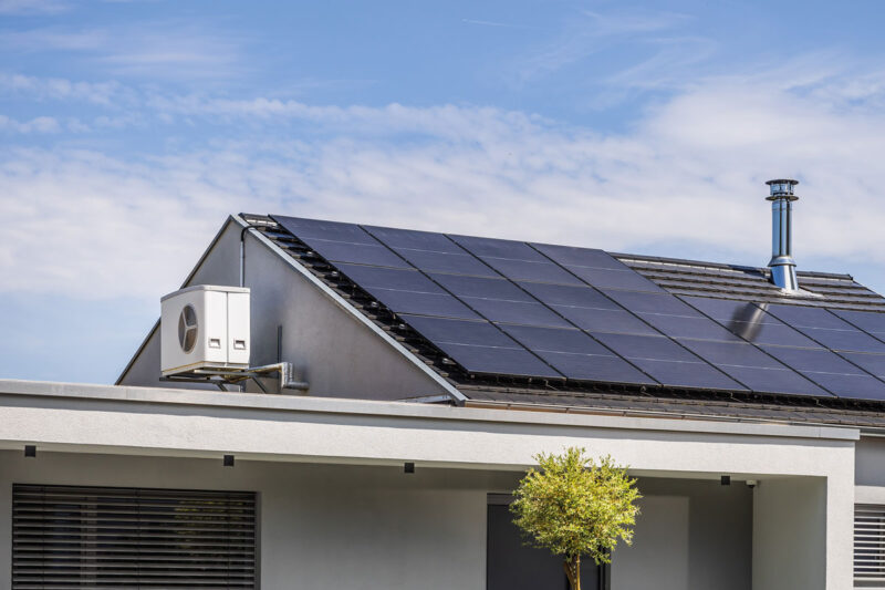 Hausdach mit PV-Anlage und am Giebel montierter Wärmepumpe.