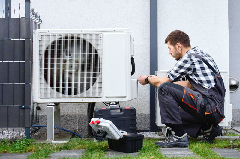 Monteur installiert die Außeneinheit einer Luft-Wärmepumpe.