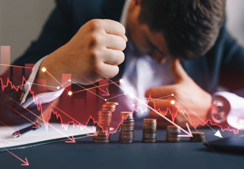 Verzweifelter Geschäftsmann angesichts hinter animierter Grafik mit abnehmenden Münzbeständen und abwärtsgerichteter Kurve.