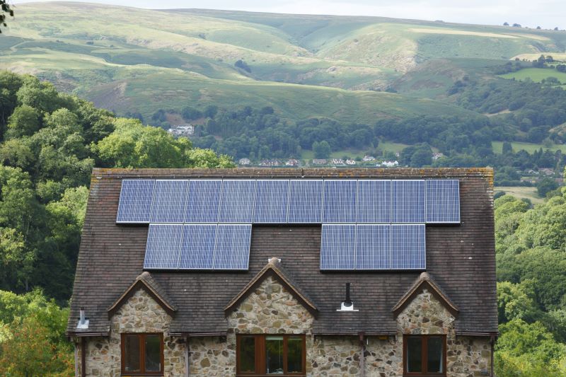 Eine alte PV-Dachanlage auf einem alten Haus in grün-hügeloger Umgebung.