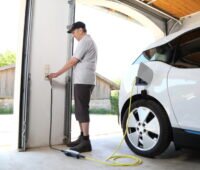 Ein Mann ladet sein E-Auto an seiner Wallbox in der Garage.