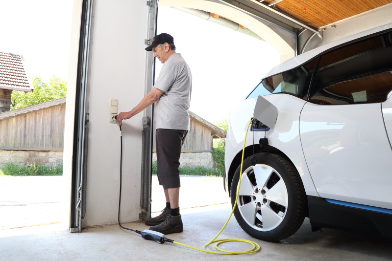 Ein Mann ladet sein E-Auto an seiner Wallbox in der Garage.