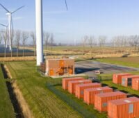 Batteriespeicherpark im Flachland mit benachbarter Windenergie und Photovoltaik.