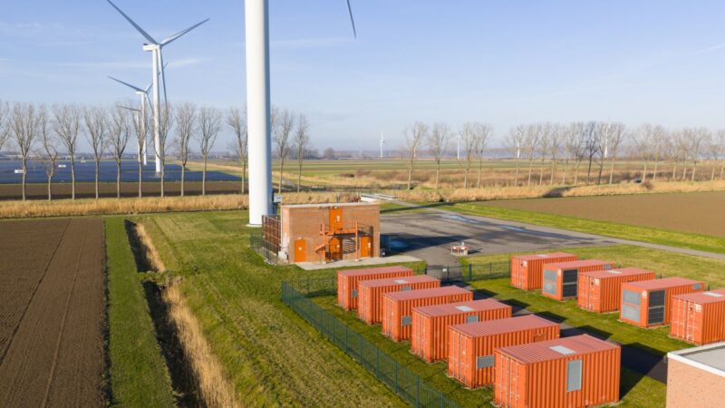 Batteriespeicherpark im Flachland mit benachbarter Windenergie und Photovoltaik.