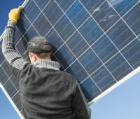 Ein. Monteur trägt ein Solarmodul.