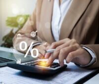 Person im Jackett betätigt Taschenrechner mit Symbolen für Steuern und Prozenten.