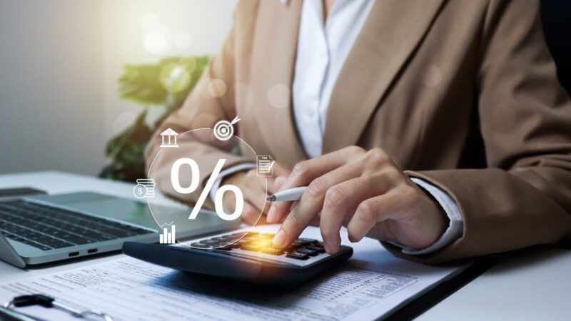 Person im Jackett betätigt Taschenrechner mit Symbolen für Steuern und Prozenten.