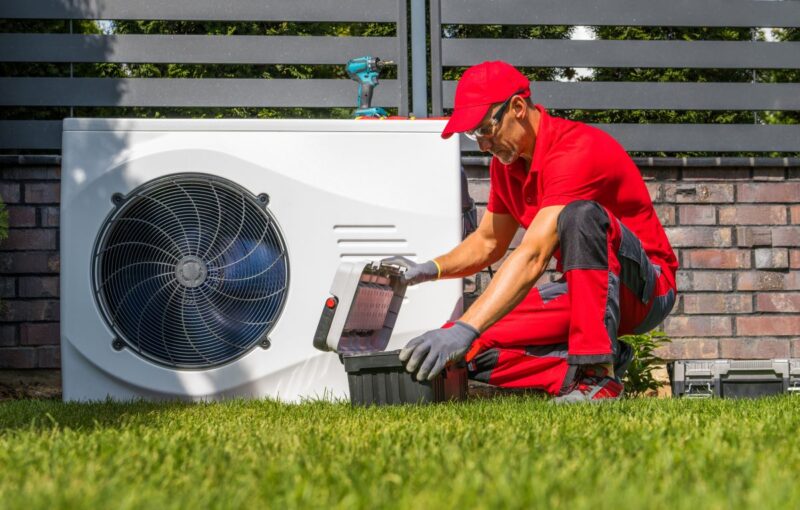 Handwerker prüft eine Wärmepumpe im Garten.