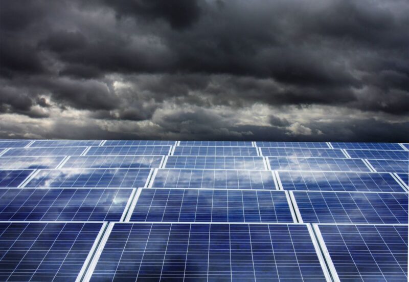 Dunkle Wolken am Horizont über einer Solaranlage im Vordergrund.