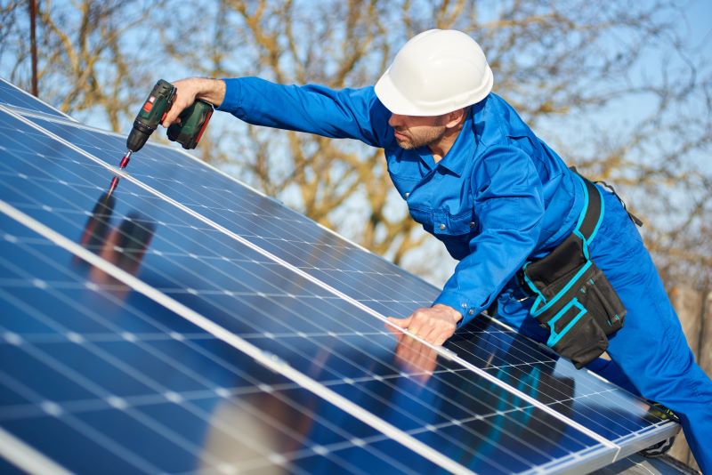 Ein Arbeiter im Blaumann montiert Solarmodule.