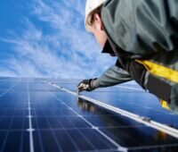 Ein Installateur montiert PV-Paneele.