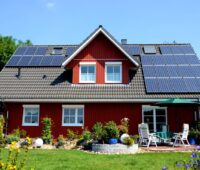 Einfamilienhaus mit PV-Anlage auf dem Schrägdach und einem Garten.