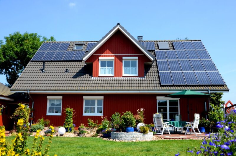 Einfamilienhaus mit PV-Anlage auf dem Schrägdach und einem Garten.