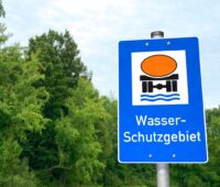 Ein Hinweisschild für ein Wasser-Schutzgebiet vor grünen Bäumen