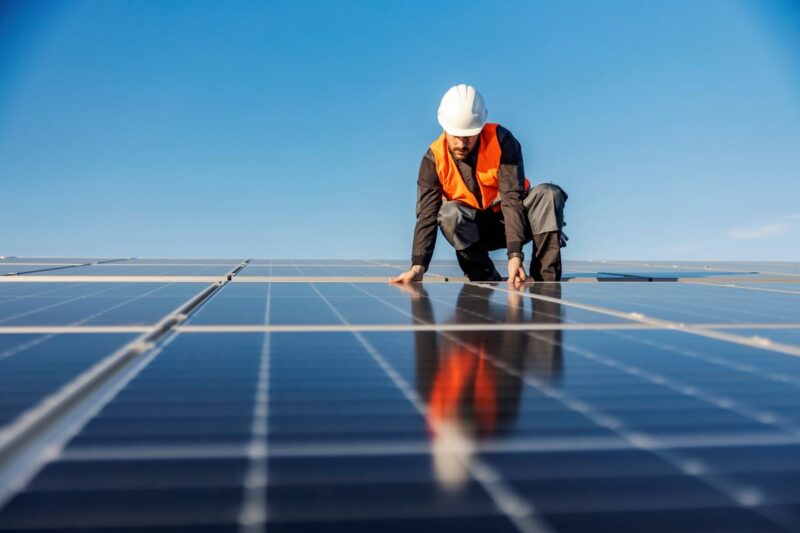 Ein Monteur verlegt PV-Module auf dem Dach.