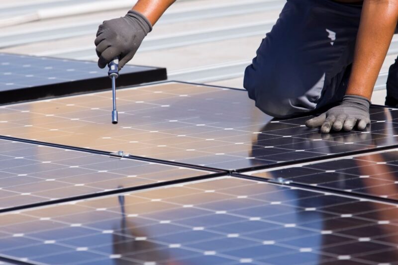 Flachdach mit PV-Modulen, die ein Handwerker im Begriff ist zu montieren.
