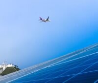 Ein Flugzeug fliegt über ein Dach hinweg, das aus Solarzellen besteht.