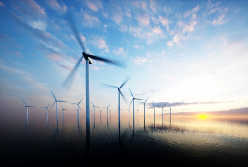 Ein Windpark auf See bei Sonnenaufgang.