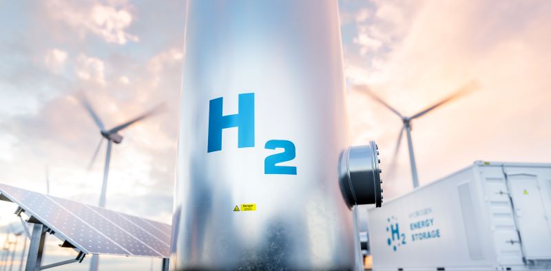 Zu sehen ist ein Wasserstofftank mit Windenergieanlagen und Photovoltaik-Modulen, Aurora hat die Kosten für grünen Wasserstoff analysiert.