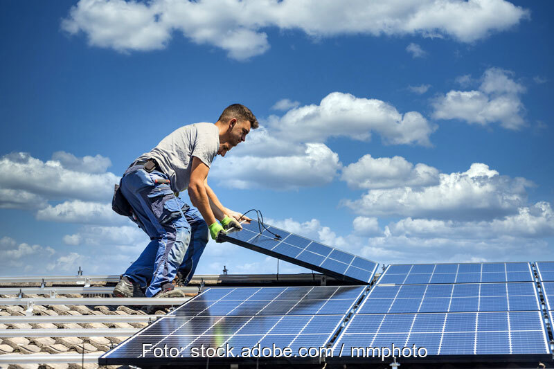 Zwei Monteure verlegen Solarmodule auf Schrägdach