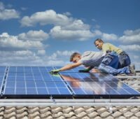 Zwei Monteure installieren eine PV-Anlage auf dem Dach.