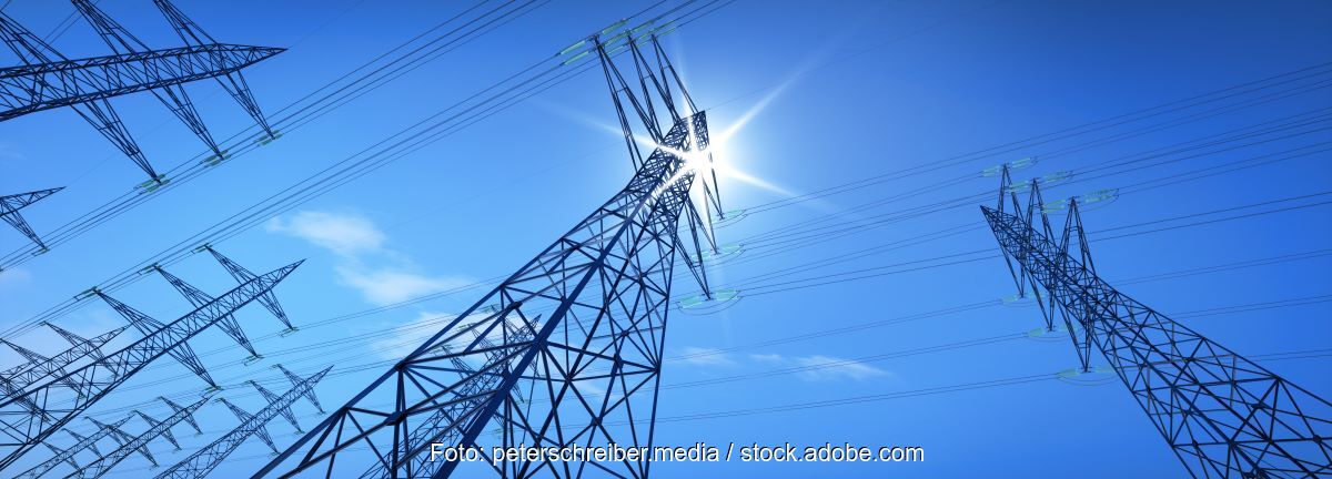 Strommasten vor Sonne am blauem Himmel.