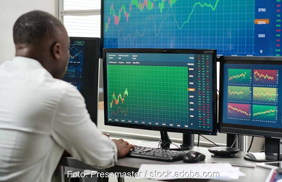 Mann vor diversen Bildschirmen mit Graphen, Tabellen und Zahlen.