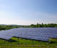 Eine PV-Freiflächenanlagen auf grüner Wiese unter blauem Himmel