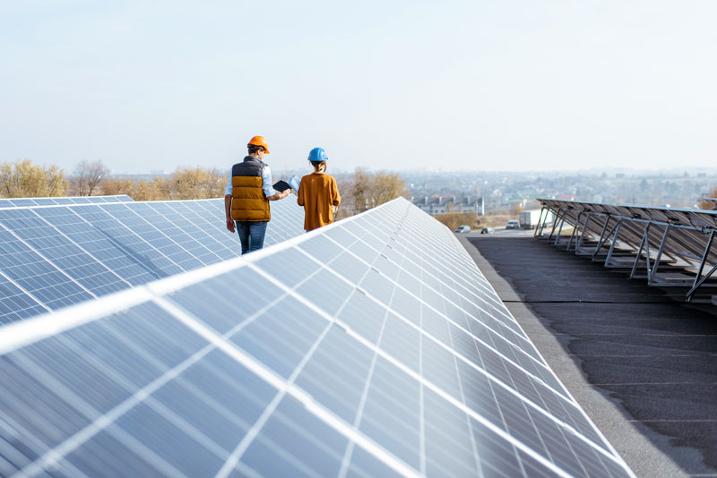 Flachdach mit Photovoltaikanlage, Ingenieure zwischen den Reiehne