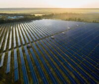 Großer Freiflächensolarpark im Flachland bei tiefstehender Sonne.