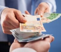 Eine Person gibt Geldscheine an eine andere Person.