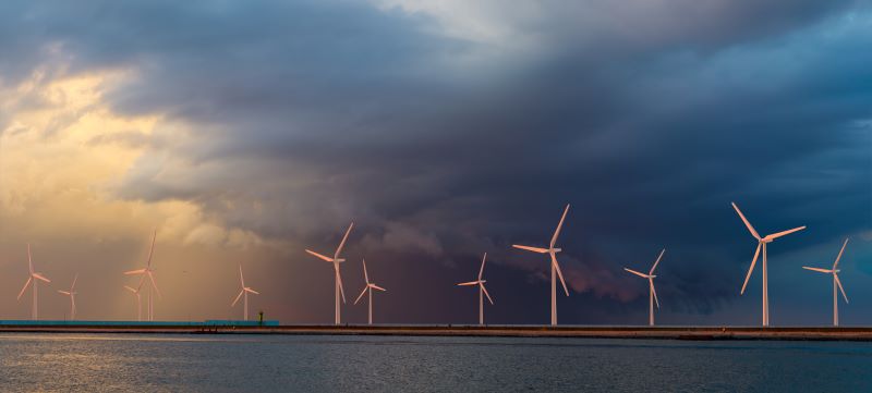 Windkraftanlagen am Meer vor dunklen Wolken.